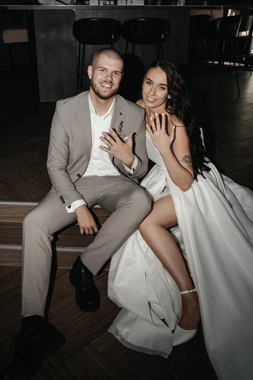 Jaunikis ir jaunoji sedi ant laiptu ir rodo savo ziedus